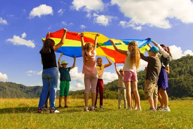 Niños jugando con un paracaídas de colores en un proyecto socioeducativo de la Fundación Ángel Linares