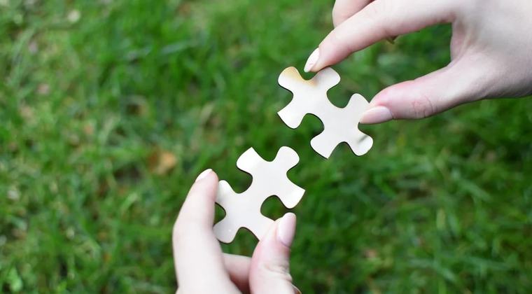 Dos manos uniendo dos piezas de un puzzle, símbolo de la colaboración de la Fundación Ángel Linares