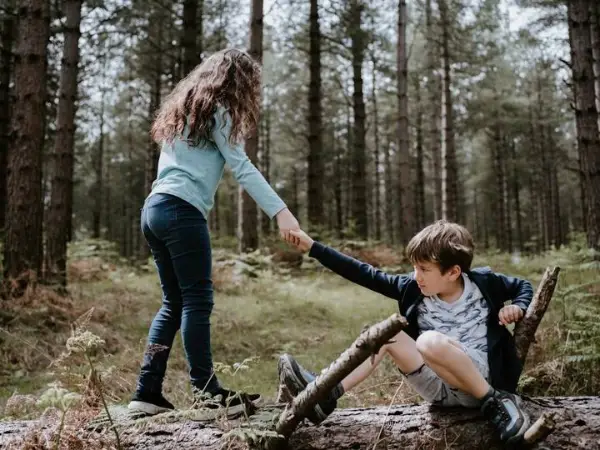 Una niña ayuda a un niño en un entorno natural, proyectos socioeducativos de la Fundación Ángel Linares